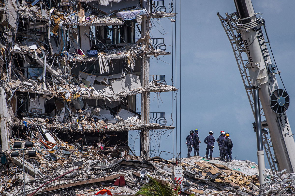 TOPSHOT - Members of the South Florida Urban Search and Rescue team look for possible survivors in the partially collapsed 12-story Champlain Towers South condo building on June 27, 2021 in Surfside, Florida. - The death toll after the collapse of a Florida apartment tower has risen to nine, the local mayor said on June 27, 2021, more than three days after the building pancaked as residents slept. 