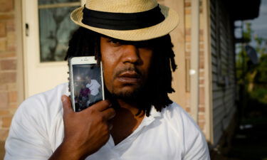 Dion Green holds a cell phone showing a picture of himself and his father