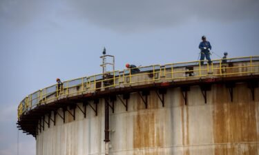 The world must limit global warming to 1.5 degrees Celsius above pre-industrial levels to limit climate crisis. Workers here stand atop a storage tank at an Imperial Oil Ltd. refinery in Sarnia