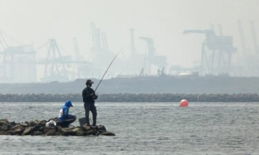 Anglers fish amid thick haze at a coastal area in Jakarta on June 20