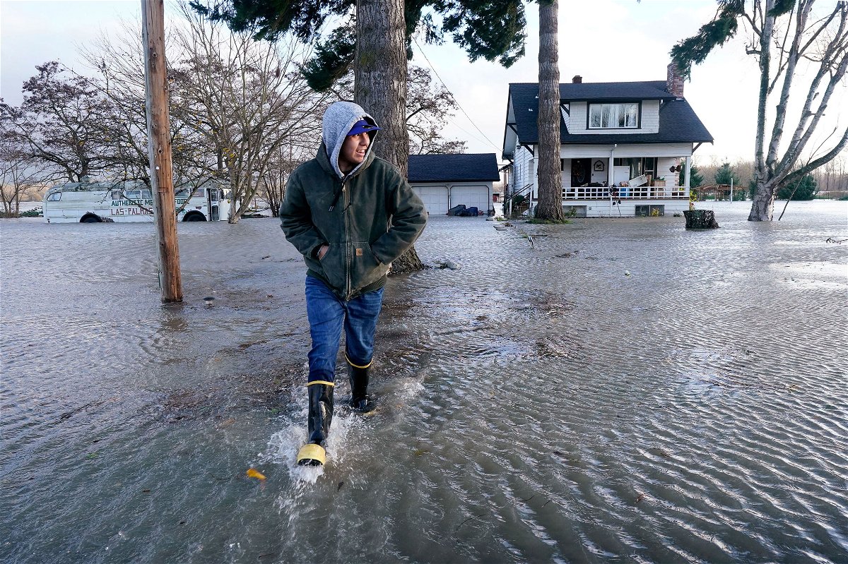 <i>Elaine Thompson/AP</i><br/>Benjamin Lopez steps from floodwater surrounding his parents home Monday in Sedro-Woolley