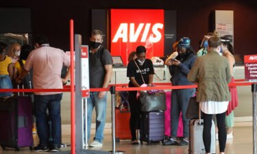 People wait in line at Avis rental agency in the Miami International Airport Car Rental Center on April 12