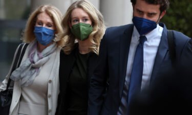 Theranos founder and former CEO Elizabeth Holmes (C) walks with her mother Noel Holmes (L) and her partner Billy Evans (R) as they arrive for her trial on December 7.