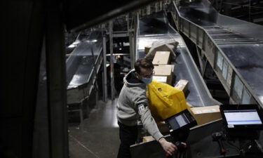 A worker loads packages into a cargo container at the UPS Worldport facility in Louisville