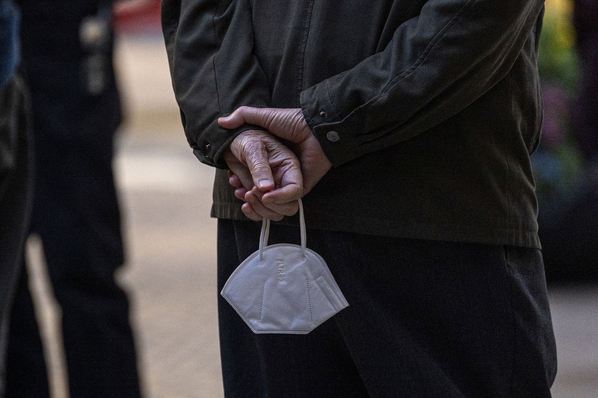 <i>David Paul Morris/Bloomberg/Getty Images</i><br/>A customer waiting to enter a restaurant holds a protective mask in San Francisco