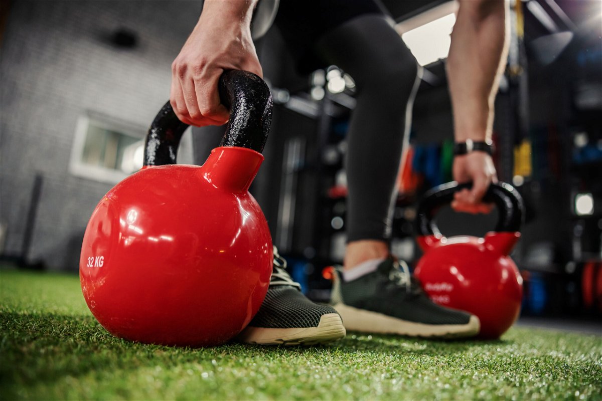 <i>dusan petkovic/Adobe Stock</i><br/>A person uses kettlebells for a strengthening exercise.