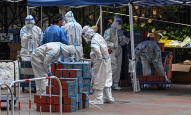 Workers wearing personal protective equipment are seen next to food delivered by the local government for residents in a compound during a Covid-19 lockdown in the Jing'an district in Shanghai on April 10.