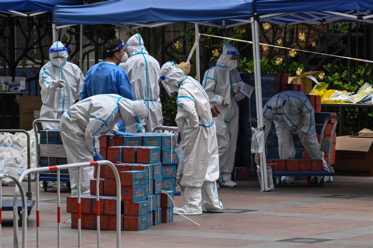 <i>HECTOR RETAMAL/AFP/Getty Images</i><br/>Workers wearing personal protective equipment are seen next to food delivered by the local government for residents in a compound during a Covid-19 lockdown in the Jing'an district in Shanghai on April 10.
