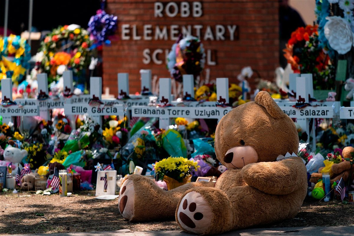 <i>Jae C. Hong/AP</i><br/>A teddy bear sits in front of crosses with the names of the 21 victims killed at Robb Elementary School.