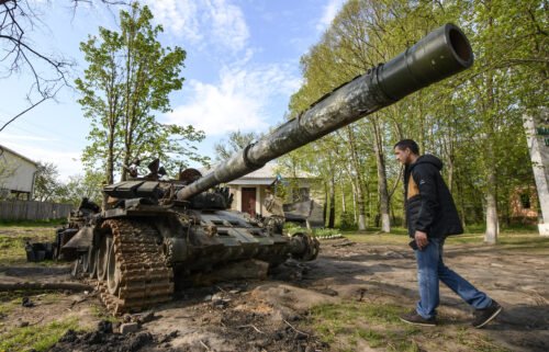 Local resident looks at the Russian military tank destroyed during Russia's invasion in Ukraine