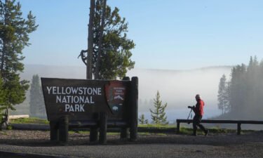 A man takes a picture at the south entrance of Yellowstone National Park