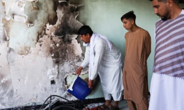 A man pours water on smouldering ashes inside a house damaged when an explosive-laden vehicle detonated amidst an attack on a Sikh temple in Kabul.