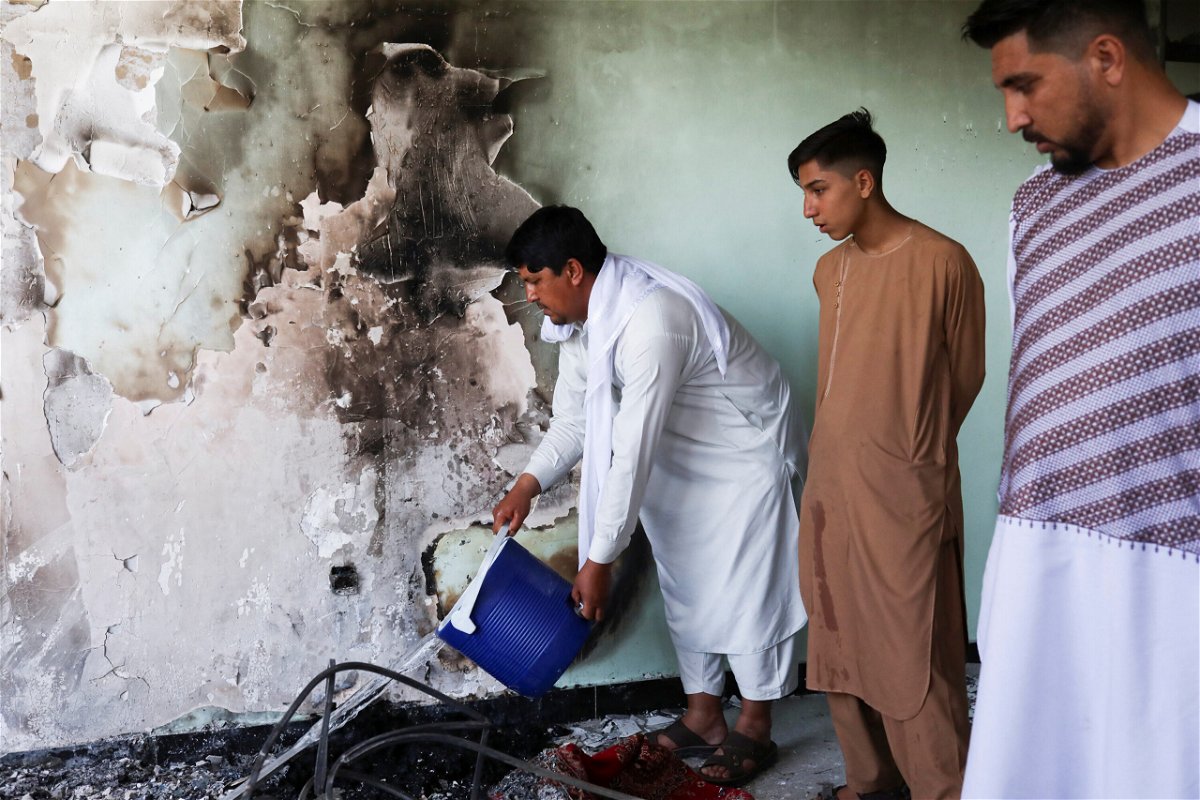 <i>Ali Khara/Reuters</i><br/>A man pours water on smouldering ashes inside a house damaged when an explosive-laden vehicle detonated amidst an attack on a Sikh temple in Kabul.