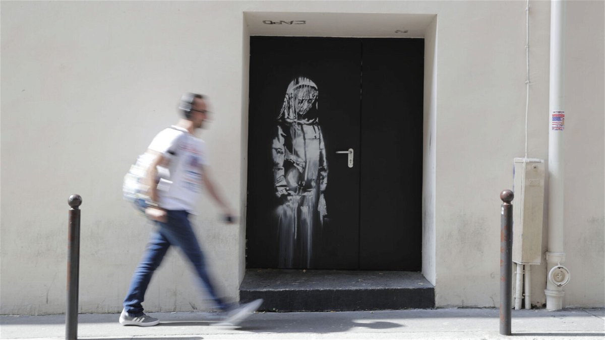 <i>THOMAS SAMSON/AFP via Getty Images</i><br/>A man walks past a recent artwork by street artist Banksy in Paris in June 2018. Eight men were convicted on June 23 by the Paris Criminal Court for stealing Banksy artwork from the Bataclan concert hall in November 2015.