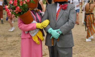 A couple dressed as flower pots walk around the site during day two of Glastonbury.
