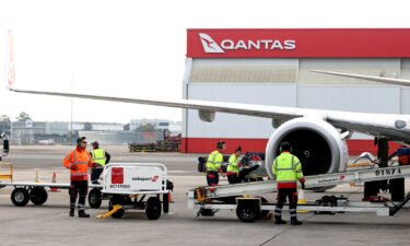 Members of the ground crew work next to an aircraft operated by Qantas Airways Ltd. at Sydney Airport in Sydney