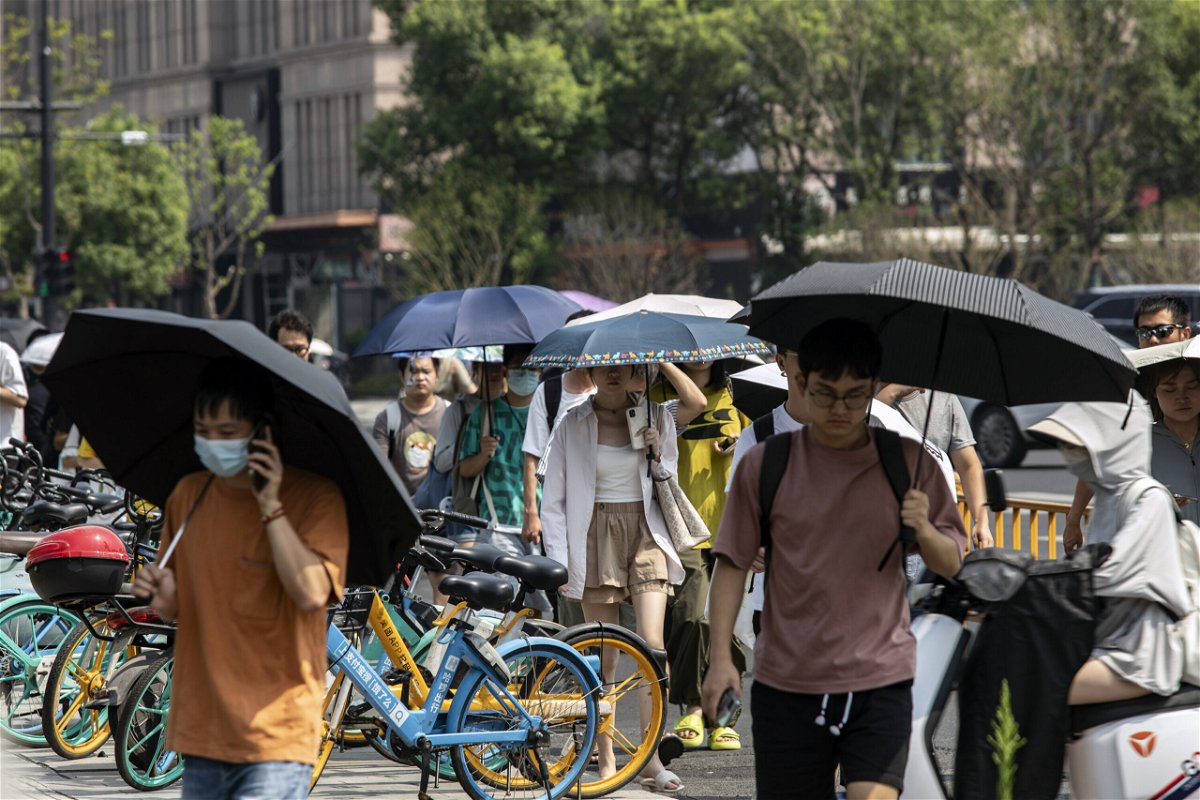 <i>Qilai Shen/Bloomberg/Getty Images</i><br/>Office workers are pictured carrying umbrellas to shield themselves from the sun in Hangzhou