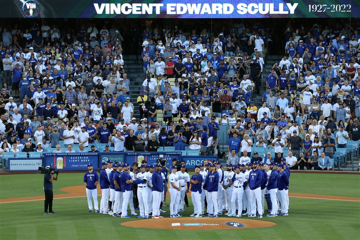 <i>Harry How/Getty Images North America/Getty Images</i><br/>Los Angeles Dodgers players and coaches stand on the field as Vin Scully is honored during a pregame ceremony.