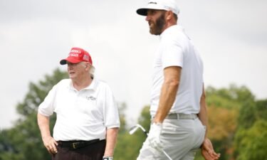 Trump looks on as Johnson plays a shot from the seventh tee during Thursday's pro-am.