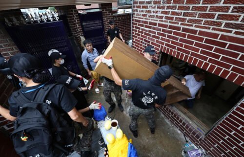 Soldiers carry debris out from a flooded house in Seoul
