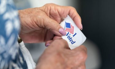 A poll worker holds a sticker that reads