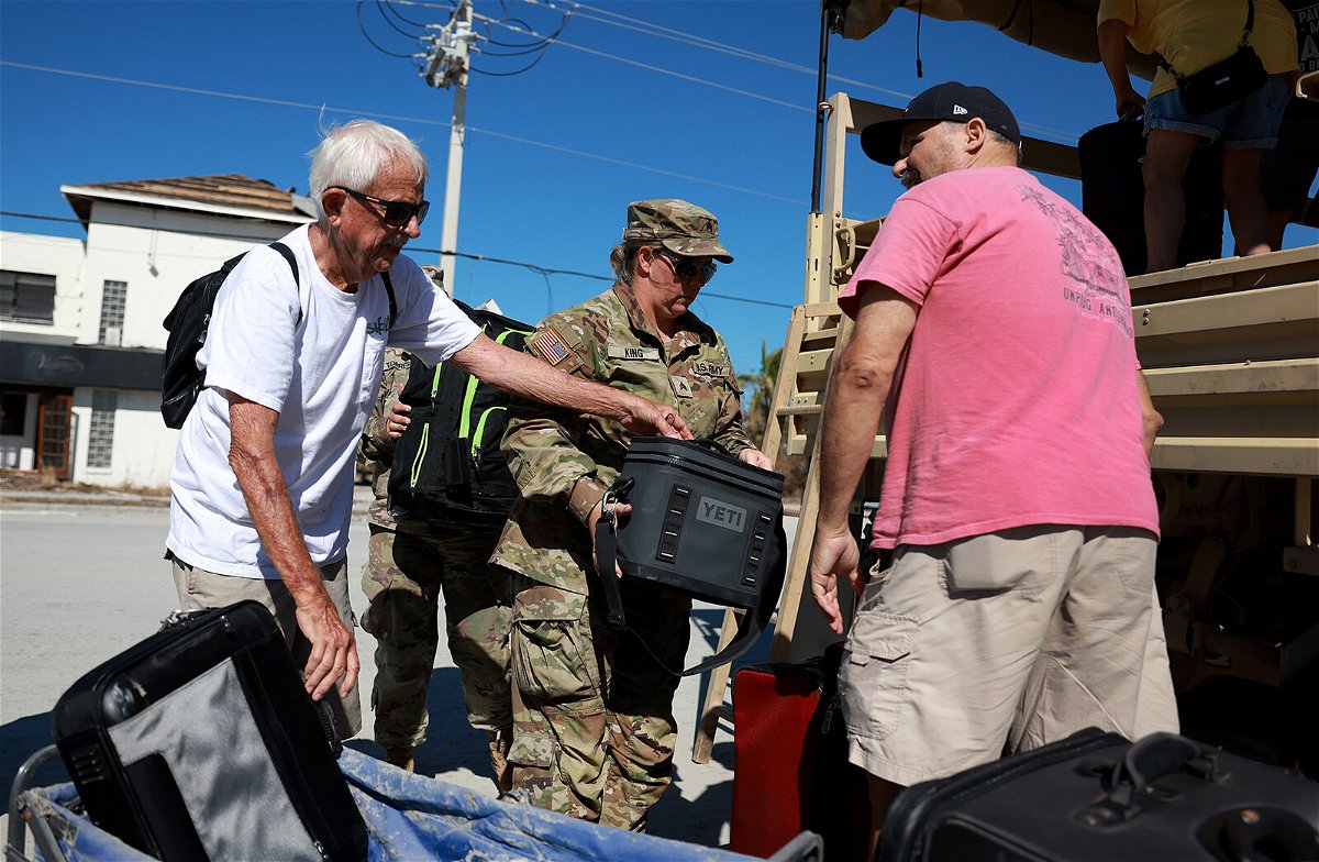 <i>Joe Raedle/Getty Images</i><br/>Florida Army National Guard members help Tim Tuitt (L) and John Davis as they are evacuated from Fort Myers Beach in the wake of Hurricane Ian.