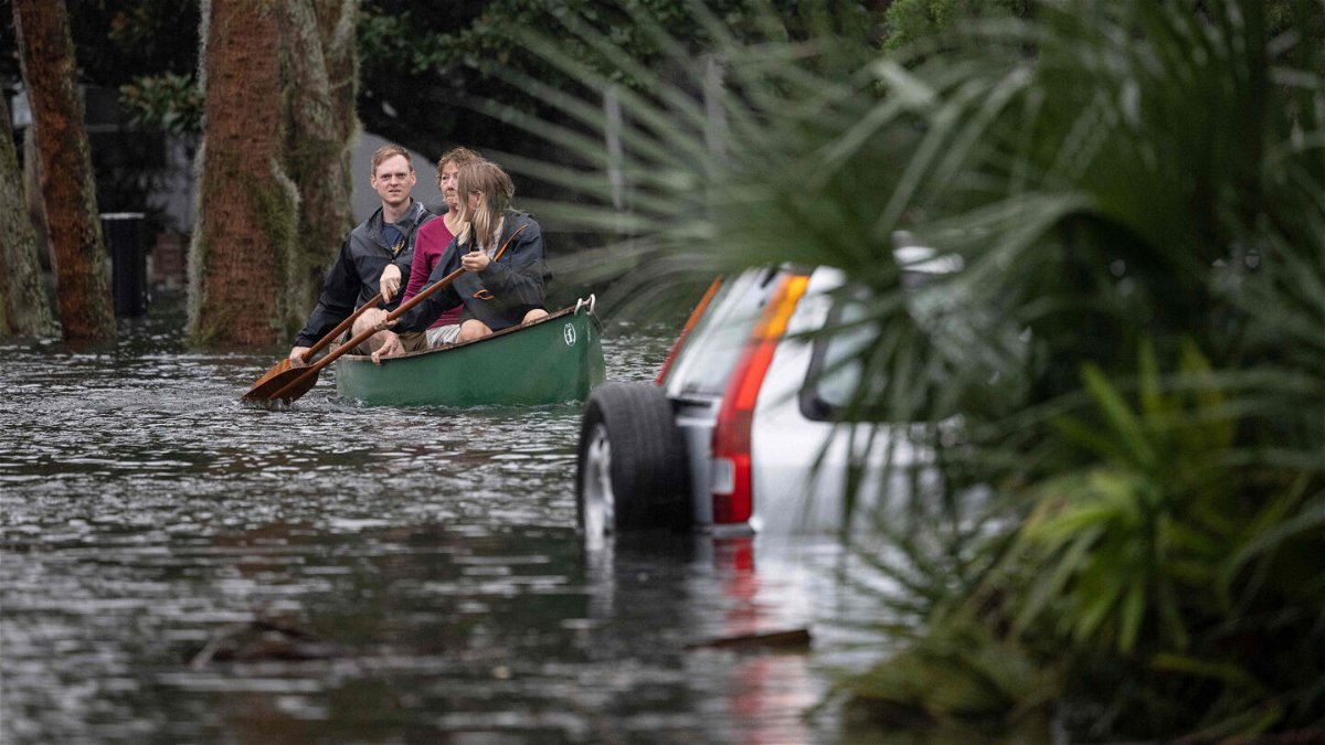 <i>Jim Watson/AFP/Getty Images</i><br/>People paddle by in a canoe next to a submerged car in the aftermath of Hurricane Ian in Orlando on September 29.