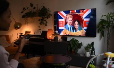 A woman poses as she watches an episode of the newly released Netflix docuseries "Harry and Meghan" about Britain's Prince Harry