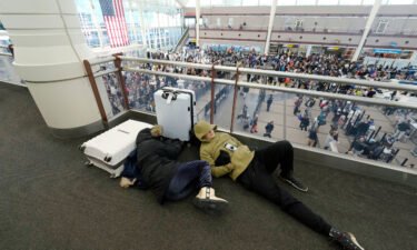 A pair of travelers sleep while others line up to pass through a security checkpoint in Denver International Airport on Friday.