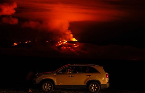 A man talks on a phone in his car alongside Saddle Road as the Mauna Loa volcano erupts near Hilo