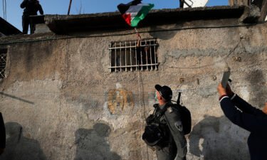 A woman waves a Palestinian flag from her window during clashes with Israeli police in February of 2022.