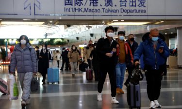 Travellers walk with their luggage at Beijing Capital International Airport in Beijing