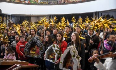 Young people hold a Birth of Christ diorama during a religious service to celebrate the Orthodox Christmas in St. Clement Cathedral in Skopje on January 6.