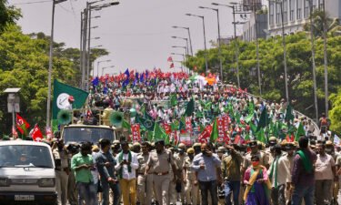 Police march in front of farmers during a protest against the central government's proposed agricultural reforms in Bangalore on March 22