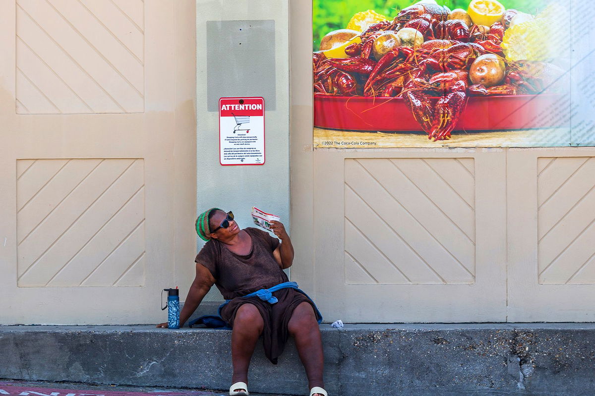 A woman fans herself outside a grocery store in New Orleans on June 28.
