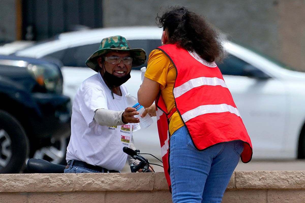 <i>Matt York/AP</i><br/>A Salvation Army volunteer gives water to a man at their Valley Heat Relief Station on July 11 in Phoenix.