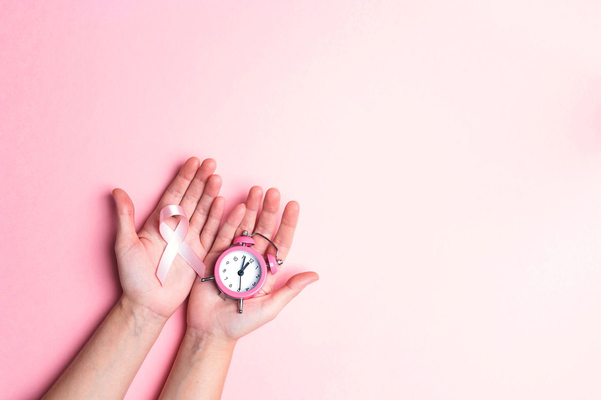 Girl hands holding pink breast cancer awareness ribbon and alarm clock. Copy space for text or design. October awareness month campaign.