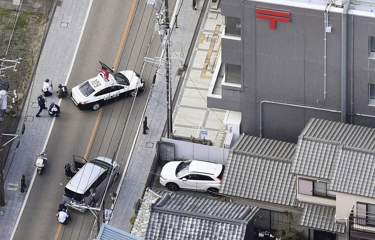 <i>Kyodo News/AP</i><br/>First responders take position outside the post office where a man is believed to holed up in Warabi