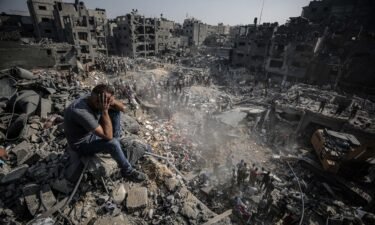 A man sits on debris as Palestinians conduct a search and rescue operation after the second bombardment to the Jabalya refugee camp in Gaza City