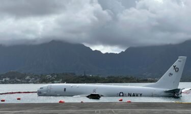 A Navy P-8A plane that overshot a runway at Marine Corps Base Hawaii and landed in shallow water offshore sits on a reef and sand in Kaneohe Bay
