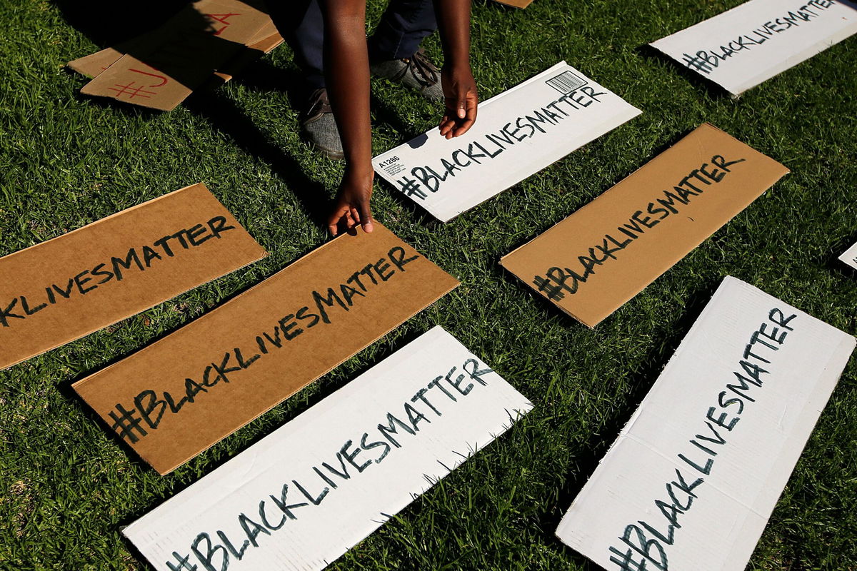 <i>Jae C. Hong/AP</i><br/>A protester picks up signs during a demonstration in Beverly Hills