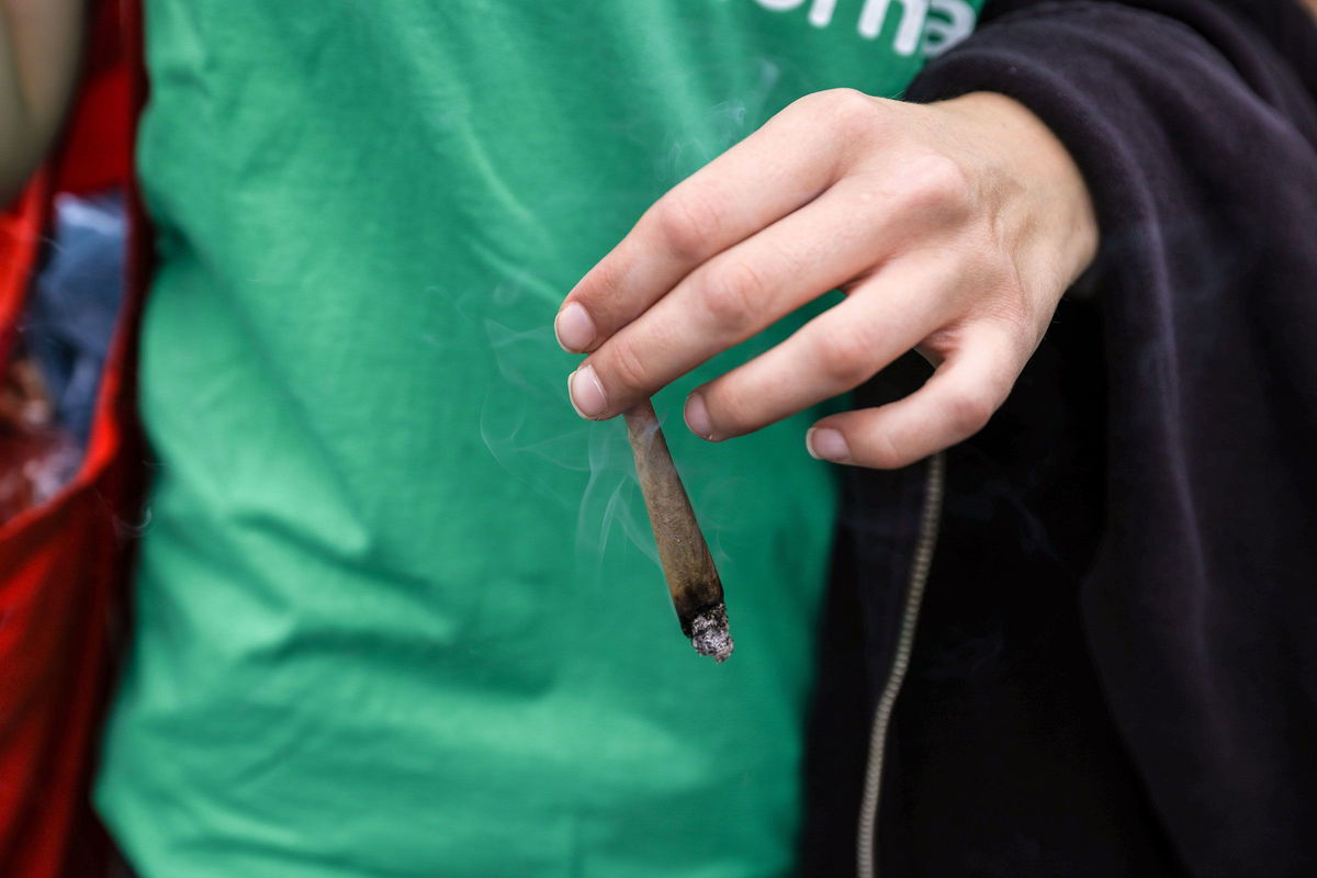 <i>Omer Messinger/Getty Images via CNN Newsource</i><br/>A participant holds a lit joint during the annual Hemp Parade on August 12