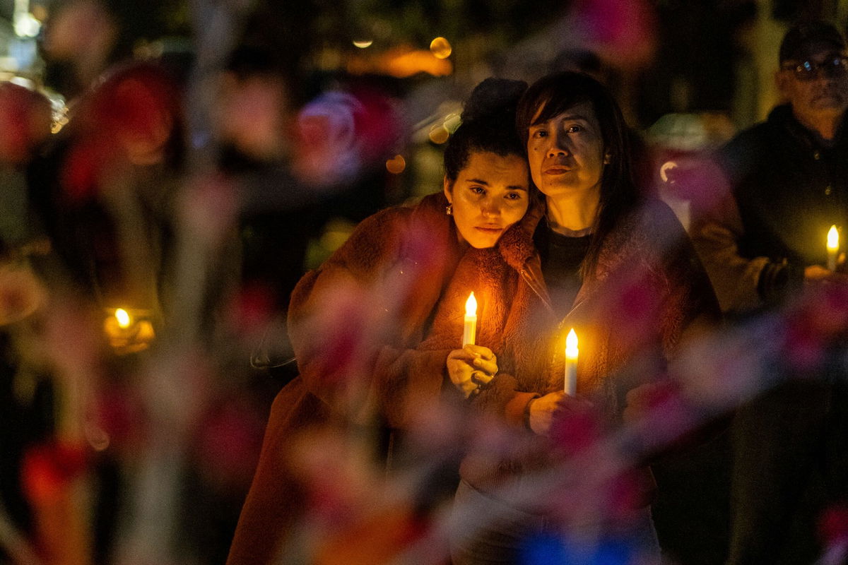 <i>Ringo Chiu/AP</i><br/>People clutch candles during a vigil on the one-year anniversary of a mass shooting on January 21