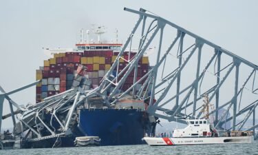 A Coast Guard cutter passes a cargo ship that is stuck under part of the structure of the Francis Scott Key Bridge after the ship hit the bridge Tuesday