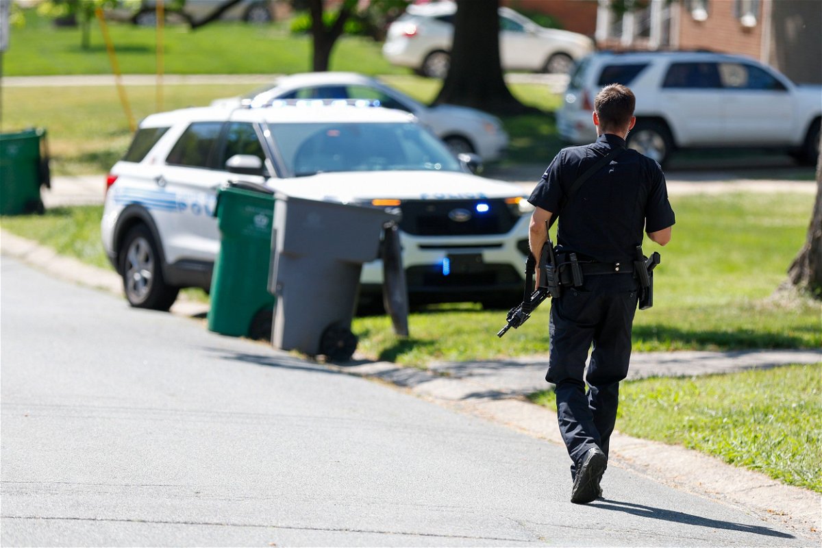 A Charlotte Mecklenburg police officer walks carrying a gun in the neighborhood where a shooting took place in Charlotte, North Carolina, Monday, April 29.