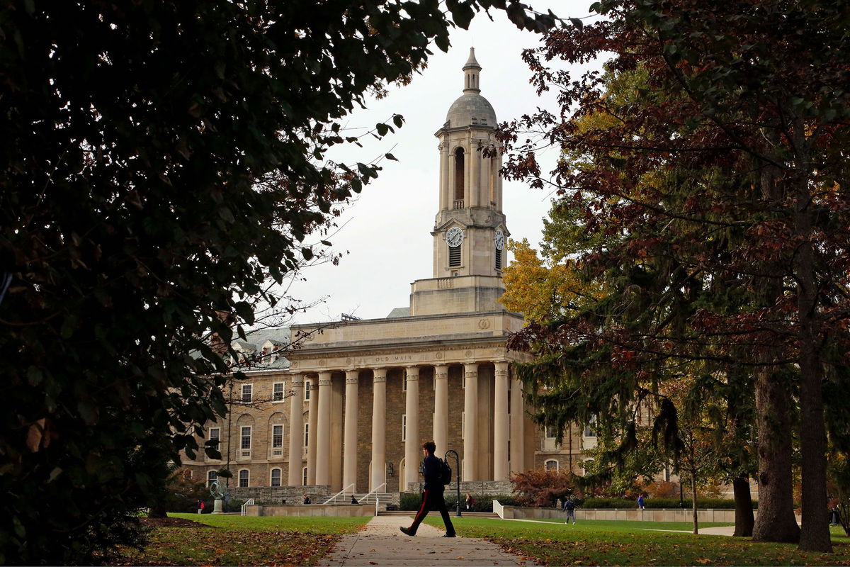 	In this November 2017 file photo, people walk by Old Main on the Penn State University main campus in State College, Pennsylvania. Many students are stuck in limbo as they wait for delayed financial aid award letters.