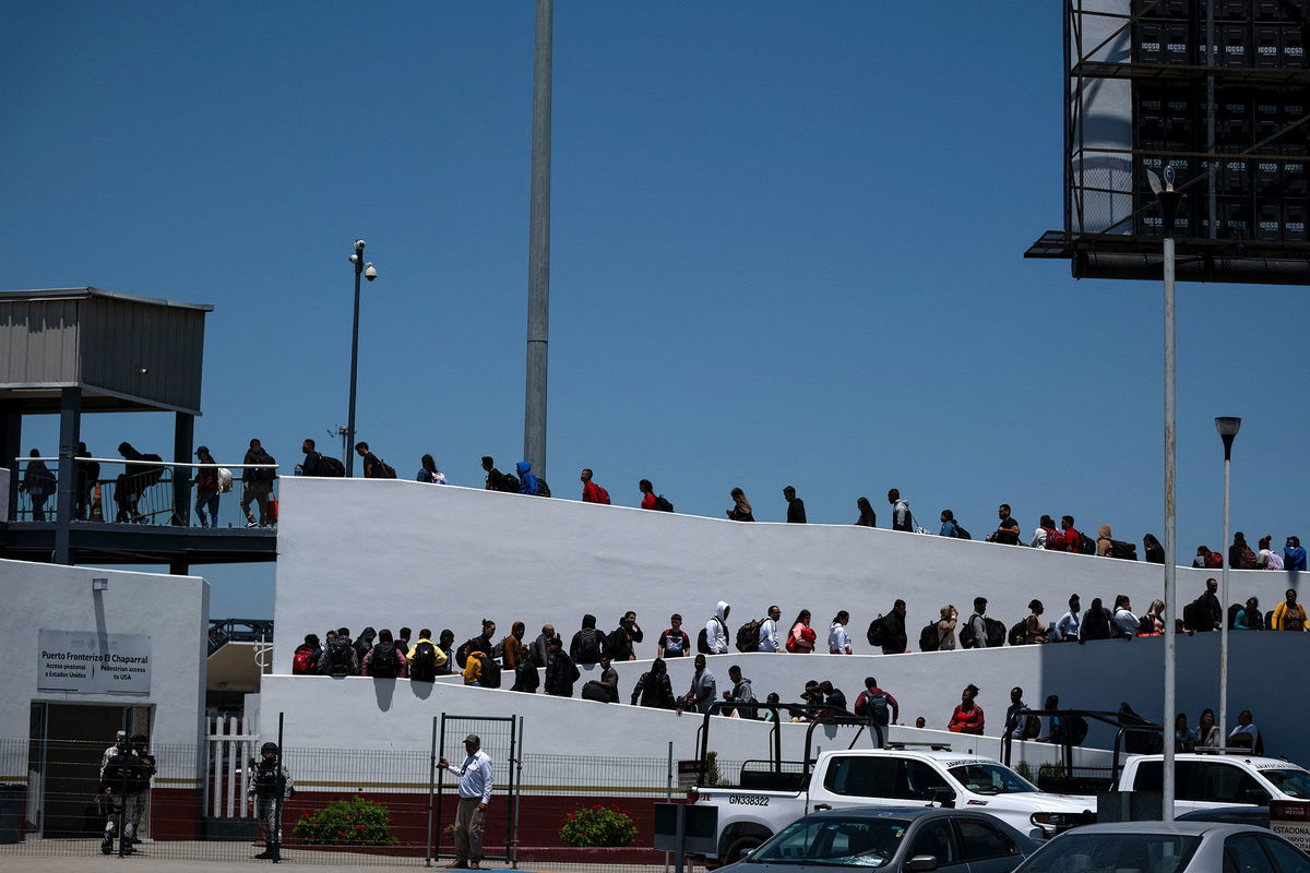 <i>Guillermo Arias/AFP/Getty Images via CNN Newsource</i><br/>Asylum seekers walk for their asylum interview appointment with US authorities at the El Chaparral crossing port in Tijuana