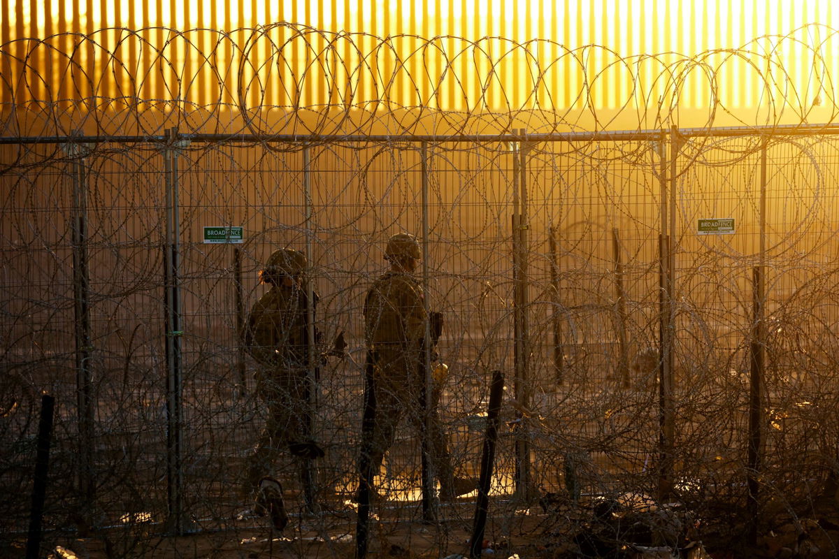 <i>Guillermo Arias/AFP/Getty Images via CNN Newsource</i><br />Migrants and asylum seekers wait to be processed by the Border Patrol between fences at the US-Mexico border seen from Tijuana