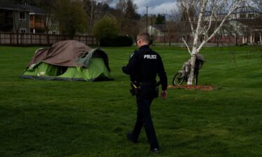 A police officer walks to check on a homeless person on March 23