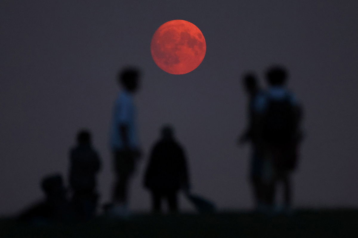 <i>Toby Melville/Reuters via CNN Newsource</i><br />People view the moon as it rises